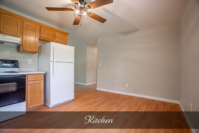 kitchen featuring under cabinet range hood, light wood-style floors, light countertops, freestanding refrigerator, and electric range oven