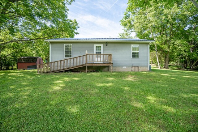 back of house featuring an outbuilding, a storage shed, crawl space, a lawn, and a wooden deck