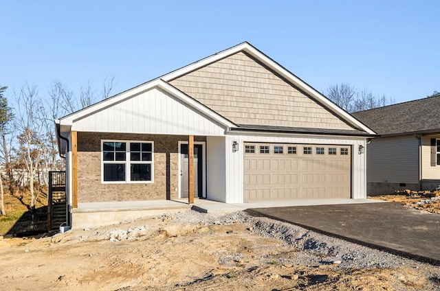 view of front of house with aphalt driveway, covered porch, brick siding, and a garage