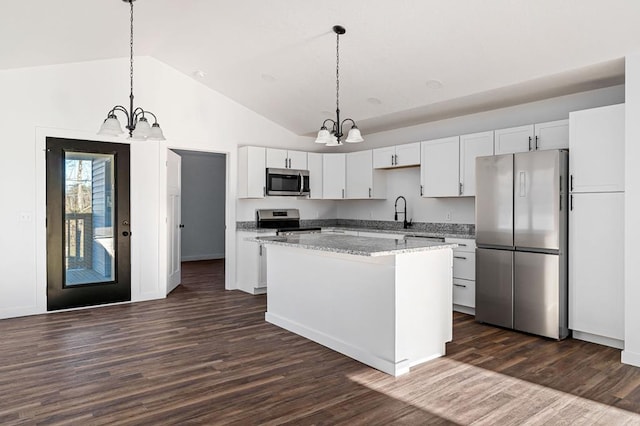 kitchen with a notable chandelier, a kitchen island, white cabinetry, hanging light fixtures, and appliances with stainless steel finishes