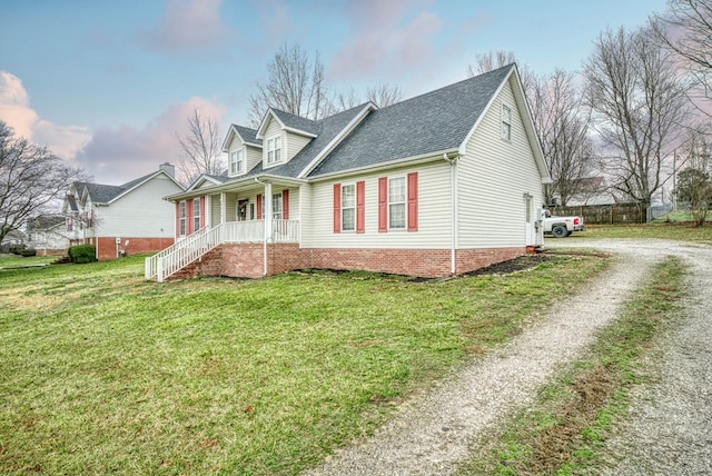 view of front of house with a shingled roof, covered porch, driveway, and a front lawn