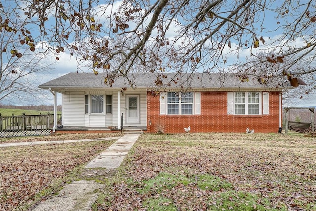 single story home featuring a porch, brick siding, and a front lawn