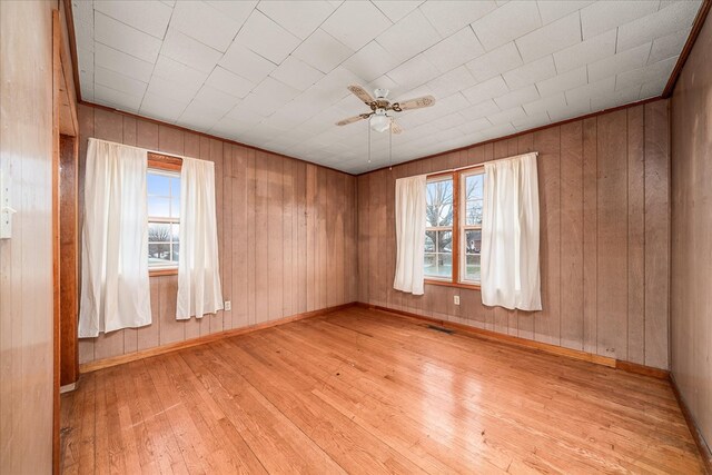 empty room with light wood finished floors, plenty of natural light, and visible vents