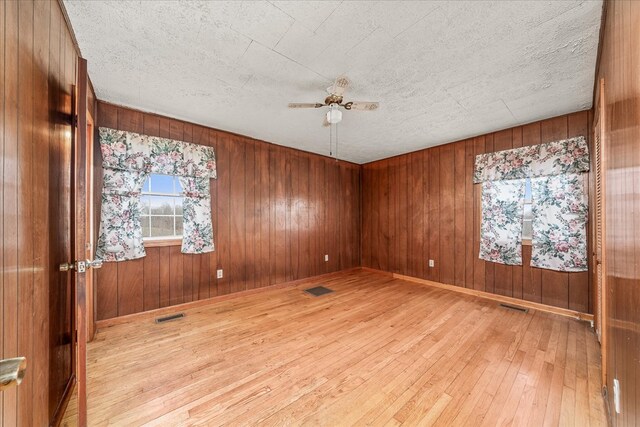 unfurnished room with ceiling fan, light wood finished floors, and visible vents