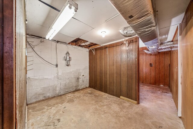 unfinished basement featuring concrete block wall and wood walls