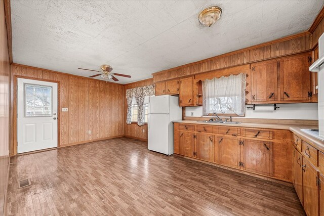 kitchen featuring a sink, light countertops, freestanding refrigerator, brown cabinets, and plenty of natural light