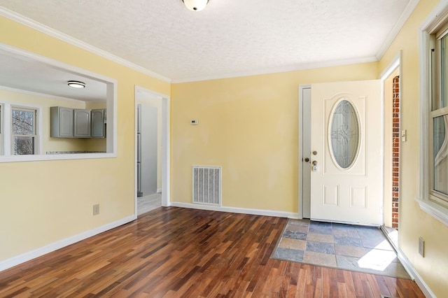 foyer with ornamental molding, visible vents, a textured ceiling, and wood finished floors