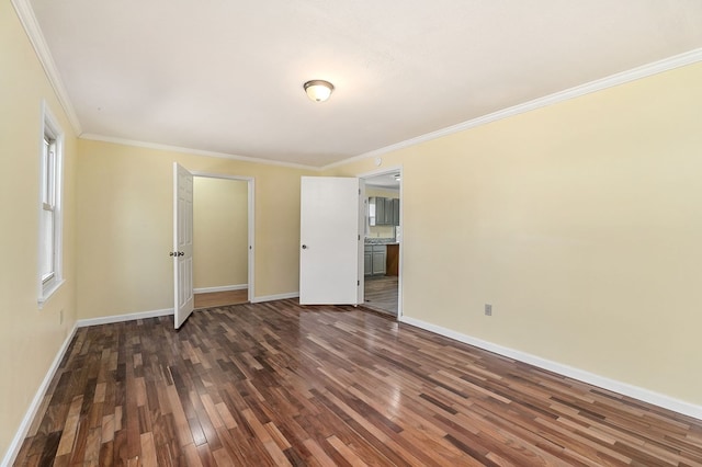 spare room featuring dark wood-style floors, crown molding, and baseboards