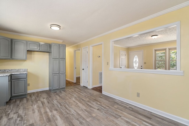 kitchen with ornamental molding, gray cabinets, light countertops, and wood finished floors