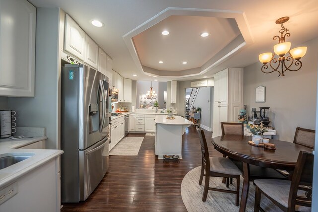 kitchen featuring light countertops, appliances with stainless steel finishes, a tray ceiling, and white cabinets