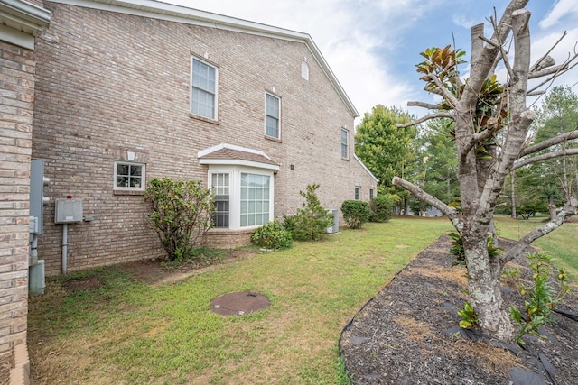 view of home's exterior featuring brick siding and a lawn