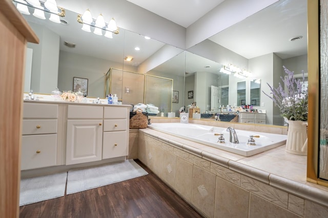 bathroom with visible vents, wood finished floors, a garden tub, vanity, and a shower stall