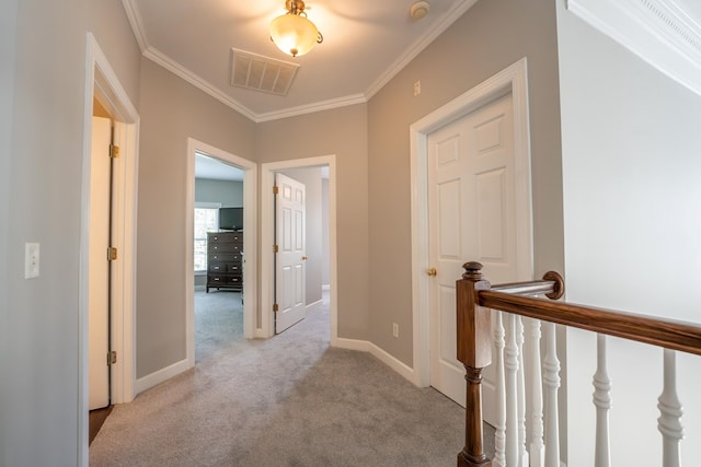 corridor featuring light colored carpet, an upstairs landing, baseboards, visible vents, and crown molding