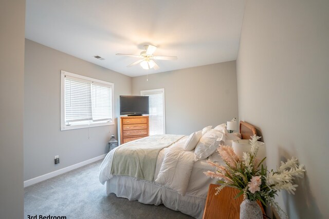 carpeted bedroom featuring a ceiling fan, visible vents, and baseboards