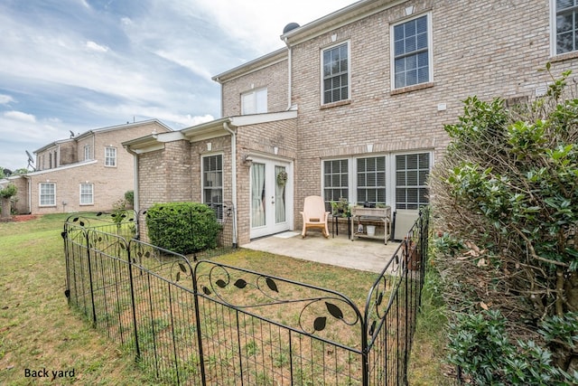 rear view of property featuring a yard, a patio area, brick siding, and fence