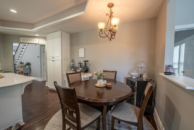 dining room with recessed lighting, a notable chandelier, dark wood-type flooring, stairs, and a raised ceiling