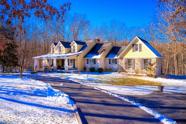 cape cod-style house featuring driveway and covered porch