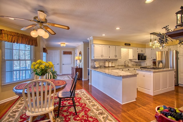 kitchen featuring dark wood-style floors, appliances with stainless steel finishes, white cabinets, and crown molding