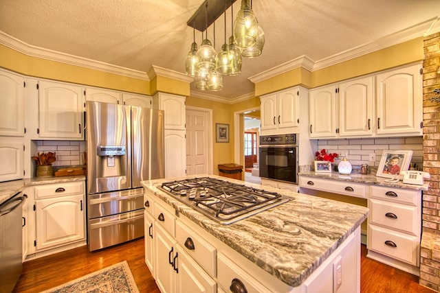 kitchen featuring dark wood-type flooring, a kitchen island, ornamental molding, appliances with stainless steel finishes, and light stone countertops