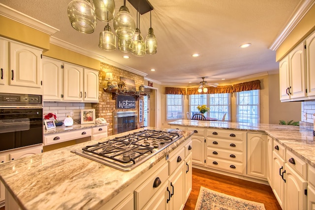 kitchen featuring ornamental molding, black oven, stainless steel gas cooktop, and a peninsula