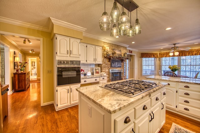 kitchen with a kitchen island, dark wood-style flooring, black oven, and stainless steel gas stovetop