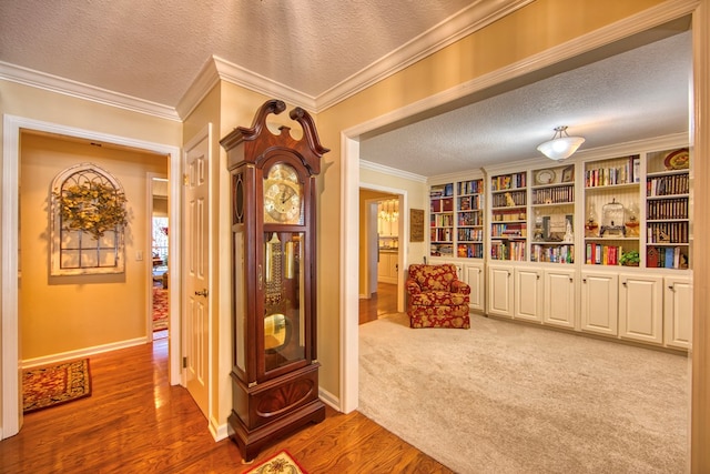 living area featuring a textured ceiling, baseboards, crown molding, and wood finished floors