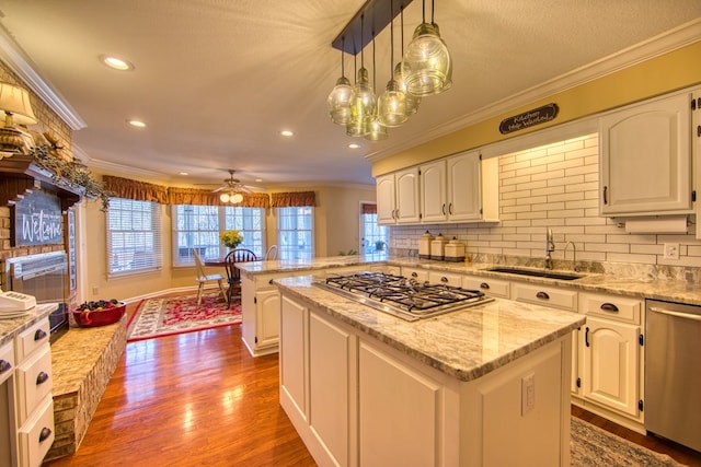 kitchen featuring ornamental molding, a peninsula, appliances with stainless steel finishes, and a sink