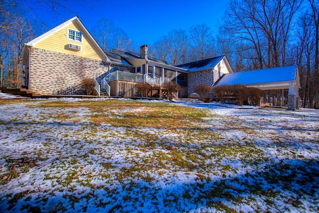 exterior space featuring a sunroom, brick siding, a chimney, and a wooden deck