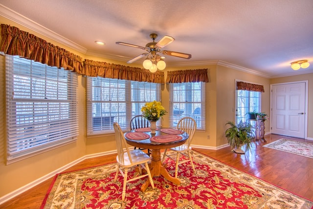 dining area featuring crown molding, a textured ceiling, baseboards, and wood finished floors