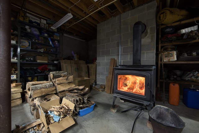 interior space featuring concrete flooring, a wood stove, and concrete block wall