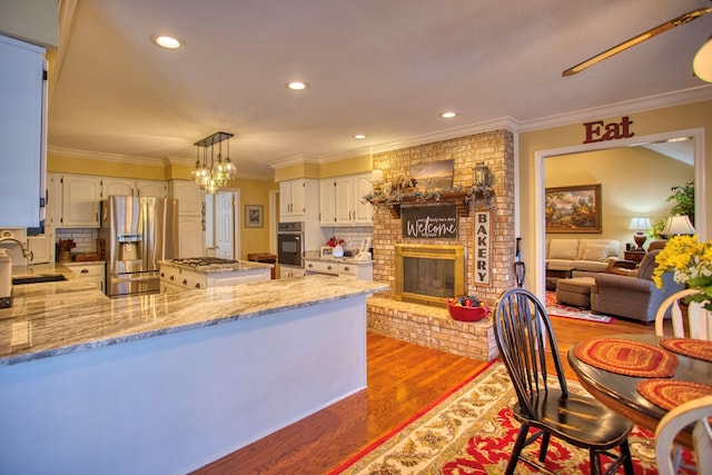 kitchen featuring wood finished floors, light stone countertops, stainless steel fridge, oven, and a peninsula