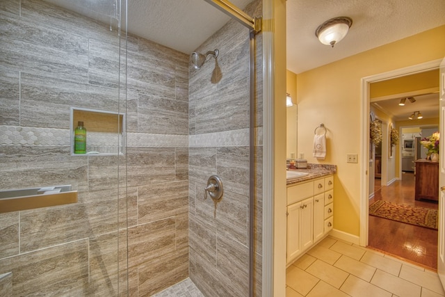 bathroom featuring a textured ceiling, a shower stall, vanity, and tile patterned floors