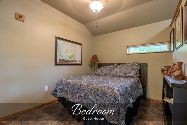 bedroom featuring lofted ceiling, stone finish flooring, baseboards, and a ceiling fan