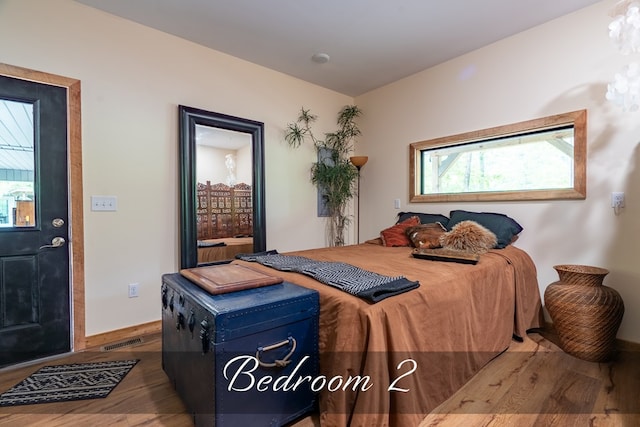 bedroom with dark wood-style flooring, visible vents, and baseboards