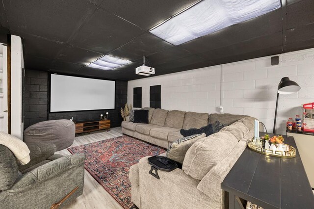 cinema room featuring concrete block wall and wood finished floors