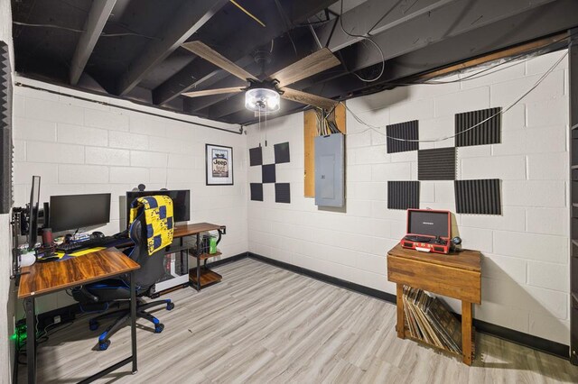 office featuring concrete block wall, light wood finished floors, ceiling fan, and electric panel