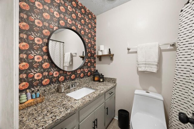 full bath with toilet, a textured ceiling, and vanity