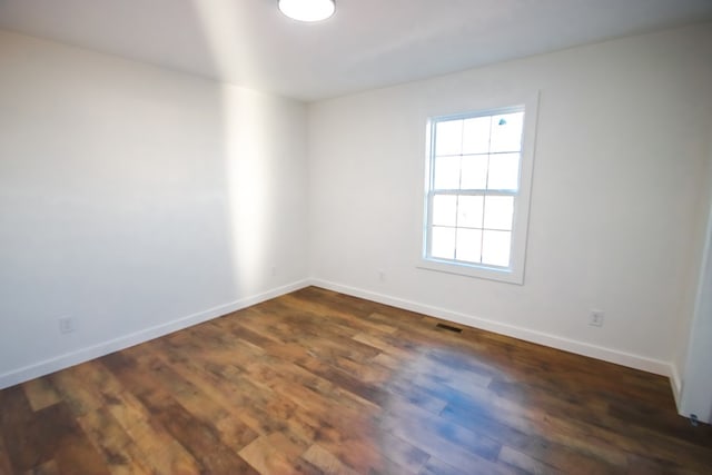 spare room with visible vents, baseboards, and dark wood finished floors