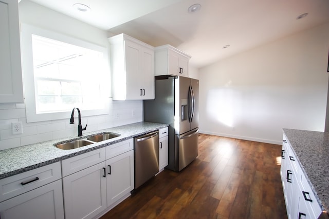 kitchen with a sink, white cabinets, appliances with stainless steel finishes, backsplash, and light stone countertops