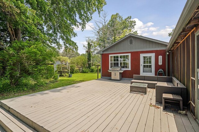 deck with a grill, an outdoor living space, and a lawn