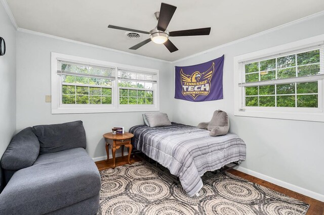 bedroom with baseboards, ornamental molding, and wood finished floors