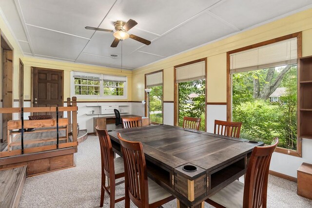 dining area with a ceiling fan, light colored carpet, and baseboards