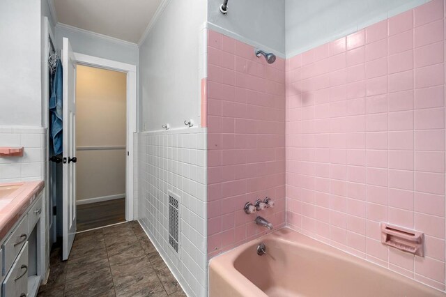 bathroom featuring wainscoting, crown molding, vanity, washtub / shower combination, and tile walls