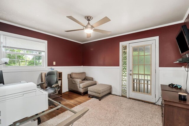 home office with a wainscoted wall, light wood-type flooring, a ceiling fan, and crown molding