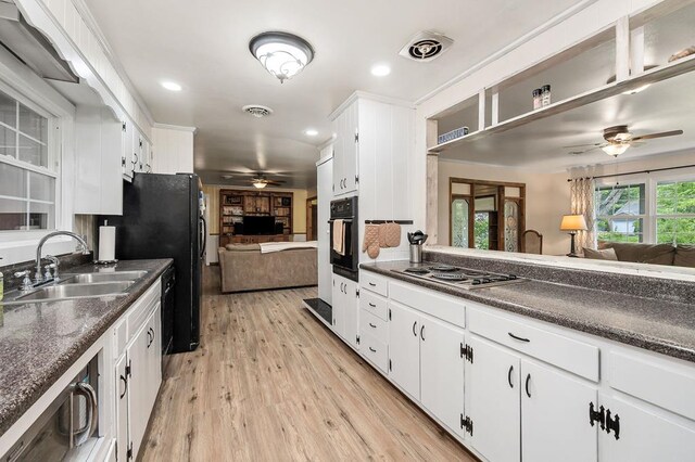 kitchen featuring dark countertops, open floor plan, oven, stainless steel gas stovetop, and white cabinetry