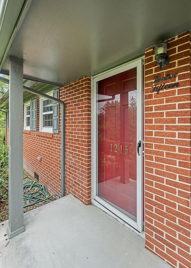 view of exterior entry featuring brick siding