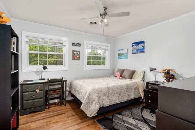 bedroom featuring ceiling fan, ornamental molding, light wood-type flooring, and visible vents