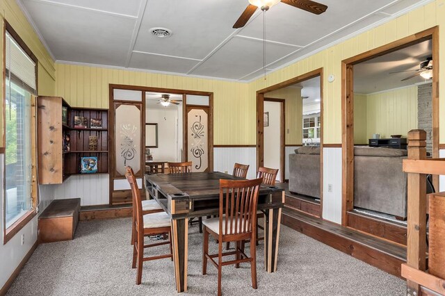 dining room featuring carpet, crown molding, visible vents, a ceiling fan, and a sunroom