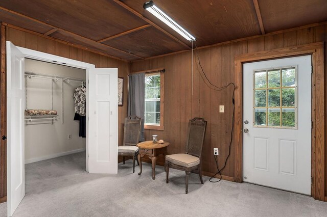 sitting room featuring wooden ceiling, light colored carpet, and wood walls