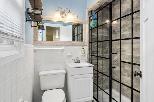 bathroom with toilet, walk in shower, tile walls, and vanity